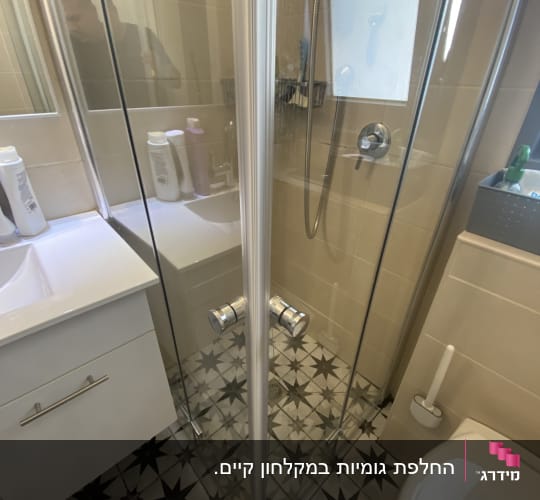 מקלחת עם דלתות זכוכית ורצפה מעוצבת